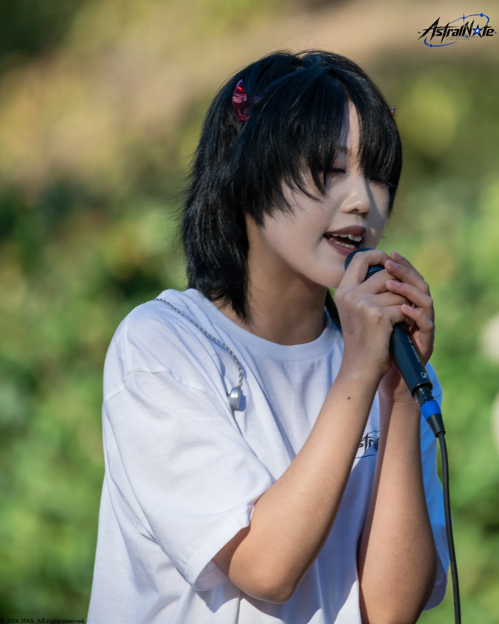 A singer performs with a microphone at Astral Note 0th LIVE.